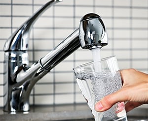 Picture of water pouring into glass from faucet